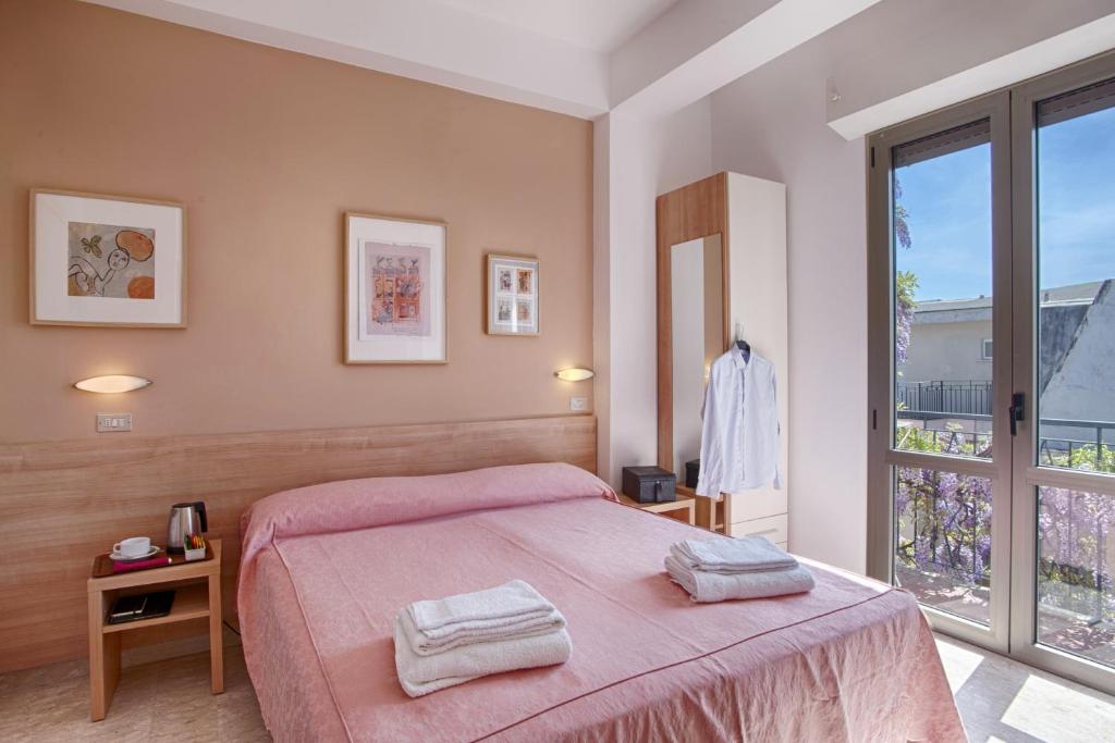 - une chambre avec un lit rose et une grande fenêtre dans l'établissement Albergo Villa Lucia, à Bellaria-Igea Marina