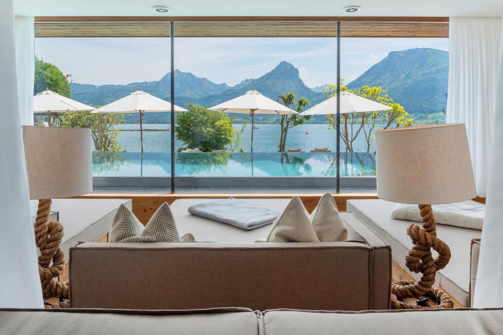 a living room with a couch and a large window at Hotel Seevilla Wolfgangsee in St. Wolfgang