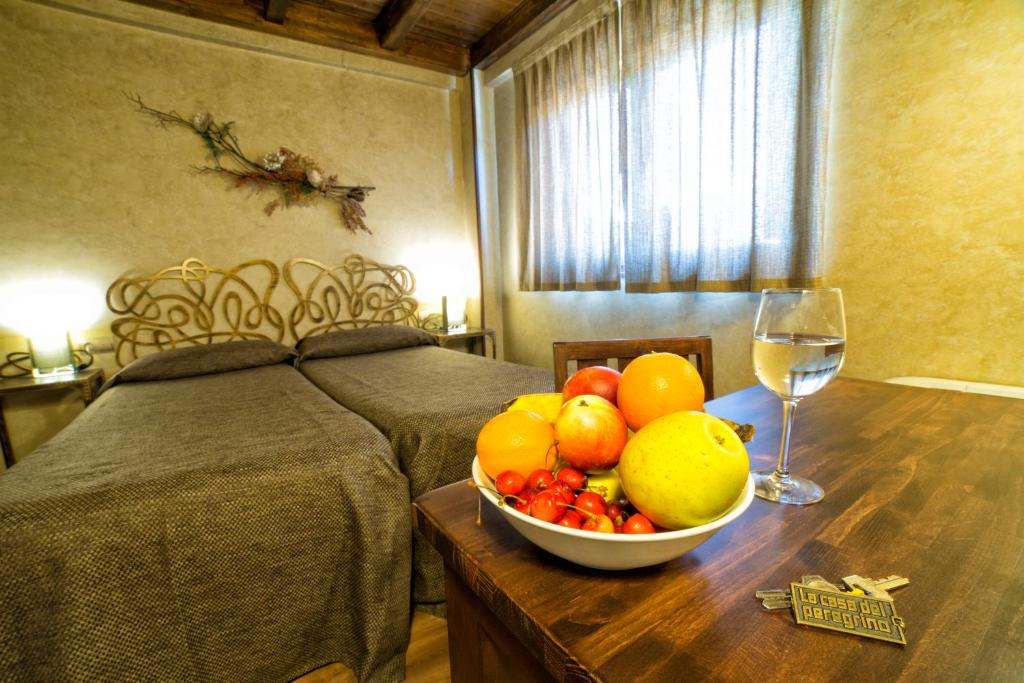 a bowl of fruit on a table with a glass of wine at Albergue La Casa Del Peregrino in El Acebo de San Miguel