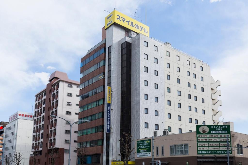 un edificio blanco alto con un cartel encima en Smile Hotel Utsunomiya Higashiguchi, en Utsunomiya