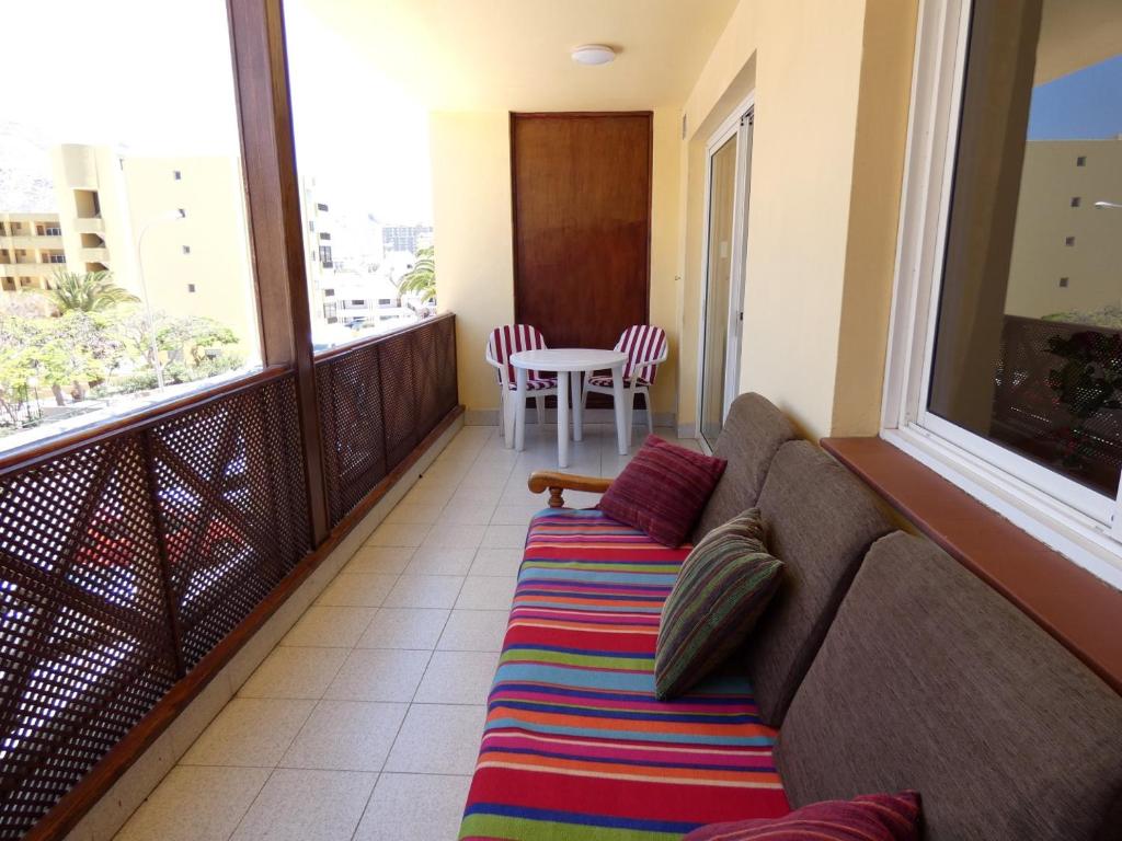 a couch on a balcony with a table and chairs at Playa Lux Los Cristianos in Los Cristianos