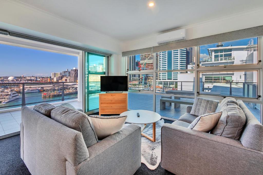a living room with two couches and a large window at Stunning Harbour & City View Studio l AIRCON & WIFI in Auckland