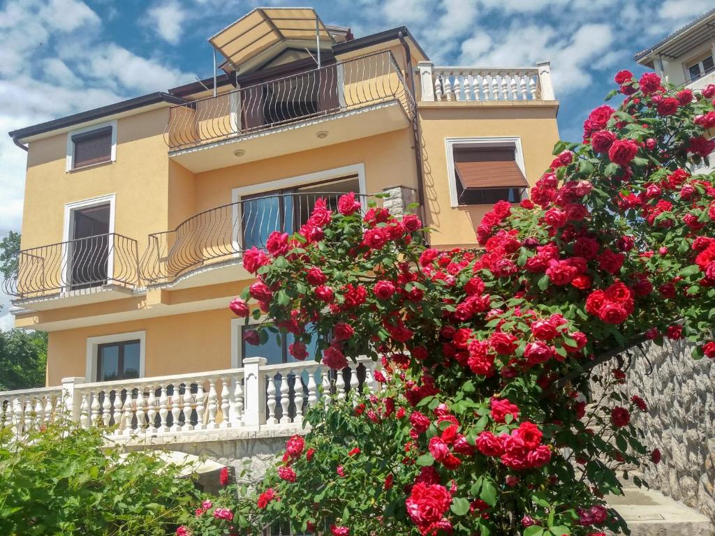 a yellow building with red flowers in front of it at Apartment Anai Rijeka in Rijeka