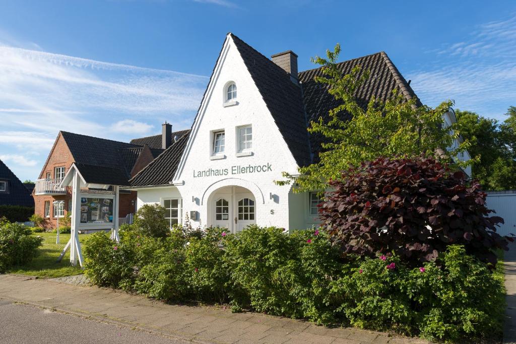 uma casa branca com um telhado preto em Hotel Landhaus Ellerbrock em Sankt Peter-Ording