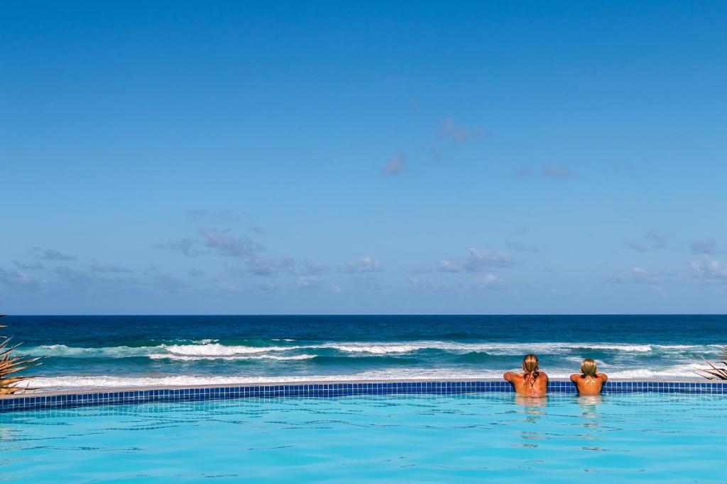 two men standing in a swimming pool next to the ocean at Massinga Beach in Massinga