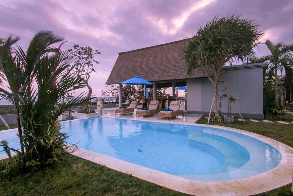 a swimming pool with chairs and a house at The Secret Spot Villas in Kusamba