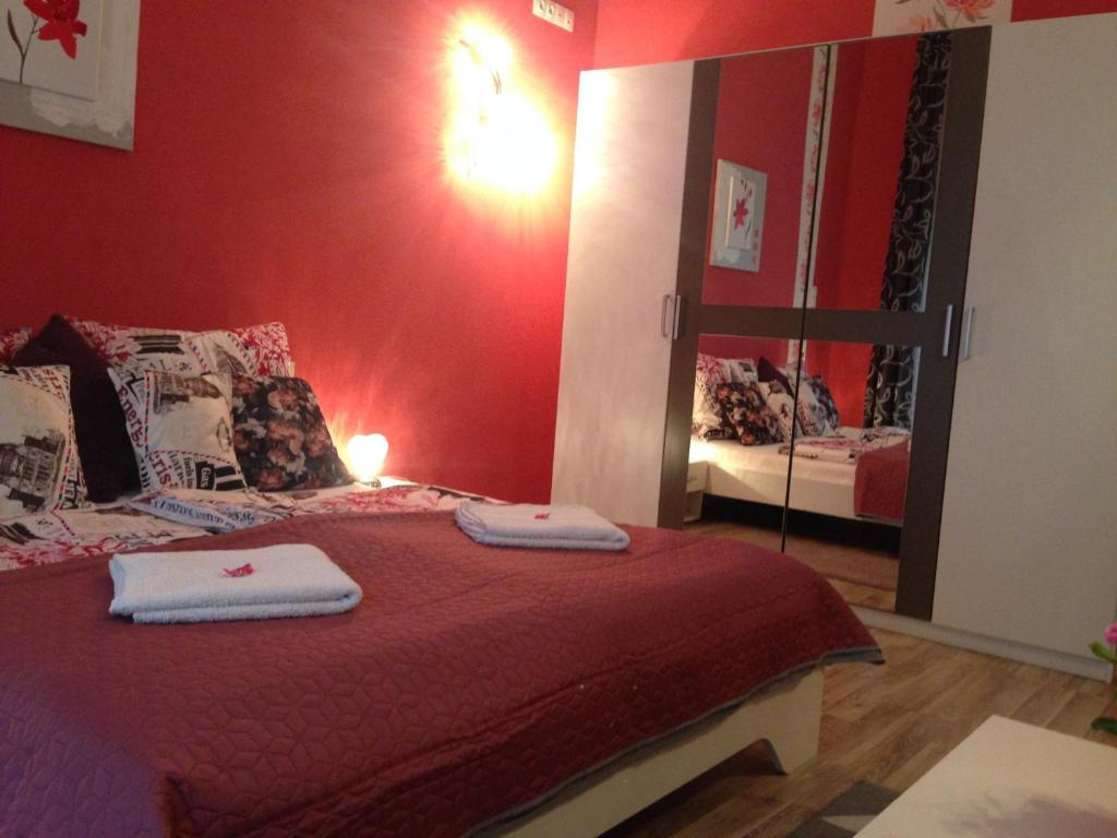 1 dormitorio con 1 cama con paredes rojas y espejo en King Residences, en Budapest