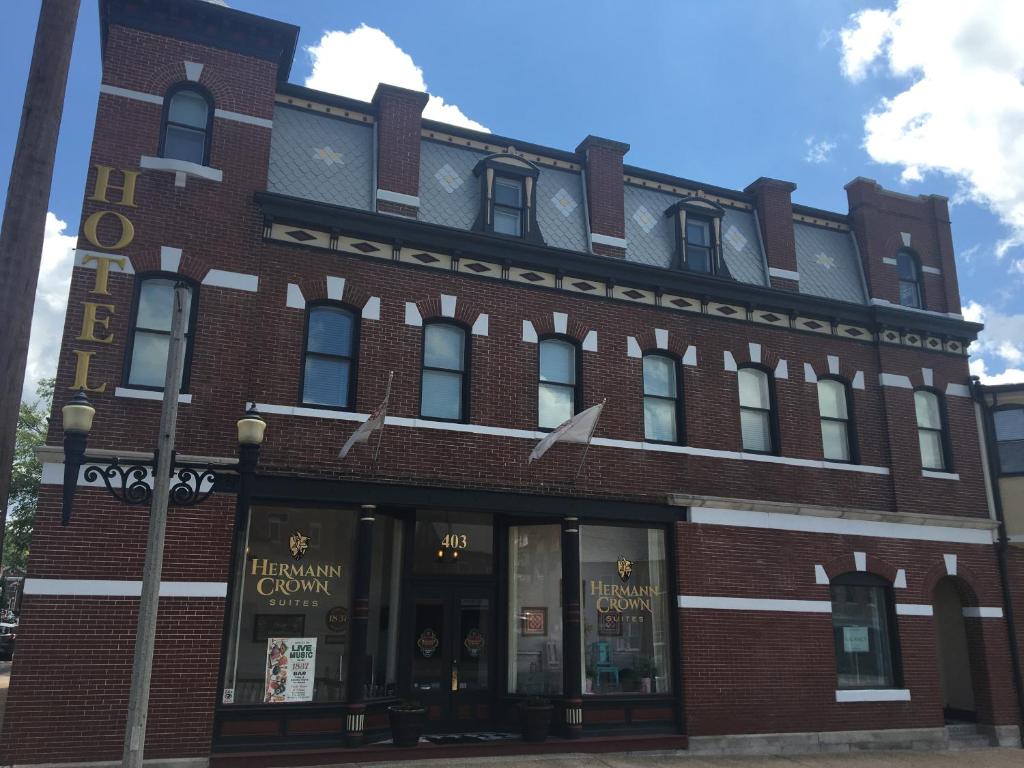 a large red brick building with a store at Hermann Crown Suites in Hermann