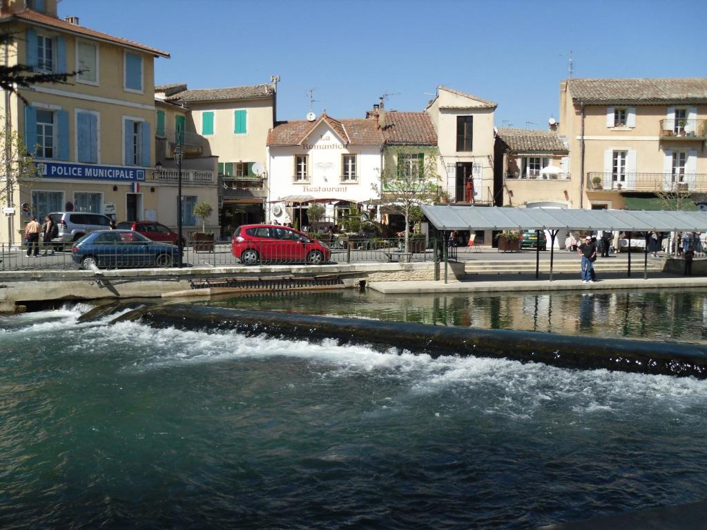 einen Fluss in einer Stadt mit Gebäuden und Autos in der Unterkunft Gite au coeur de Provence in LʼIsle-sur-la-Sorgue