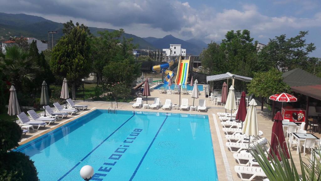 a large swimming pool with chairs and umbrellas at Melodi Club Apart in Davutlar