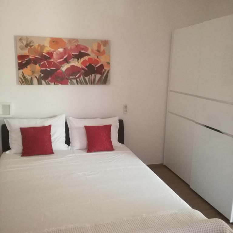 a bedroom with two beds with red pillows and a painting at Apartman Stipe in Jelsa