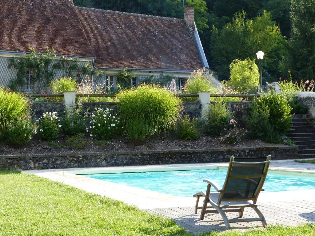 een stoel in het gras naast een zwembad bij Gite de la Vigneraie in Athée-sur-Cher