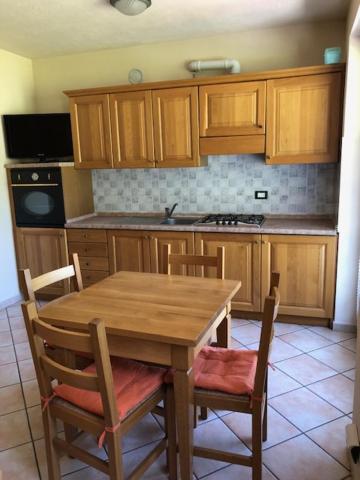 cocina con mesa de madera y armarios de madera en Monolocale Belvedere vda La Thuile CIR 0067, en La Thuile