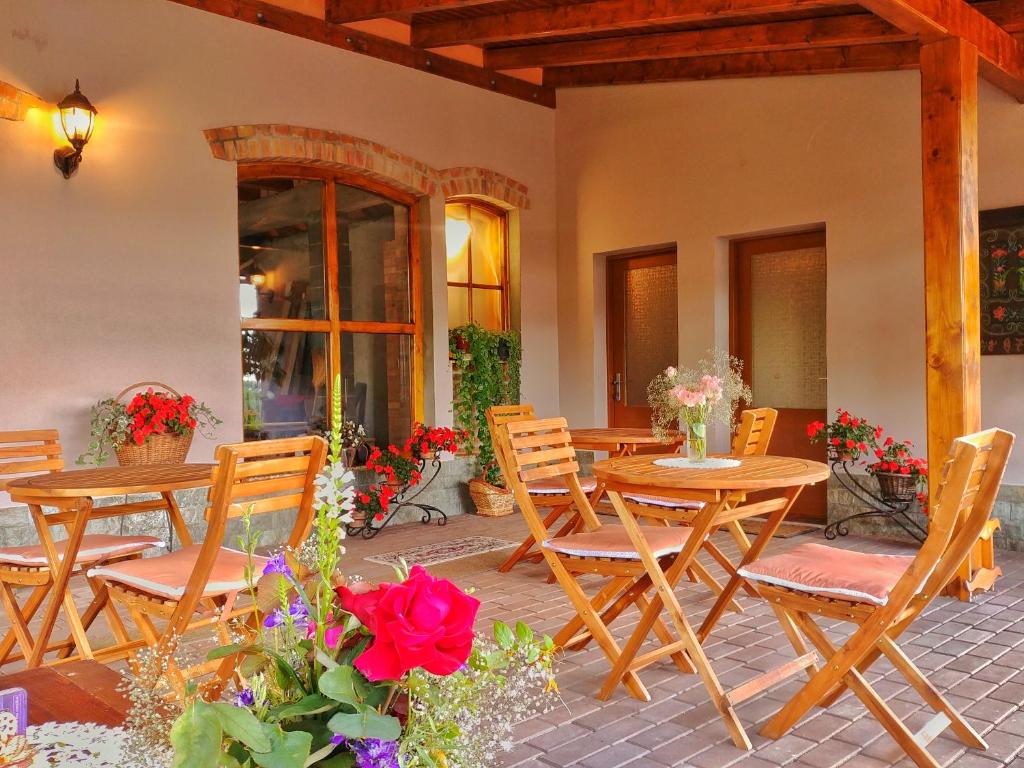 un patio con mesas de madera, sillas y flores en Casa Adam en Sighişoara