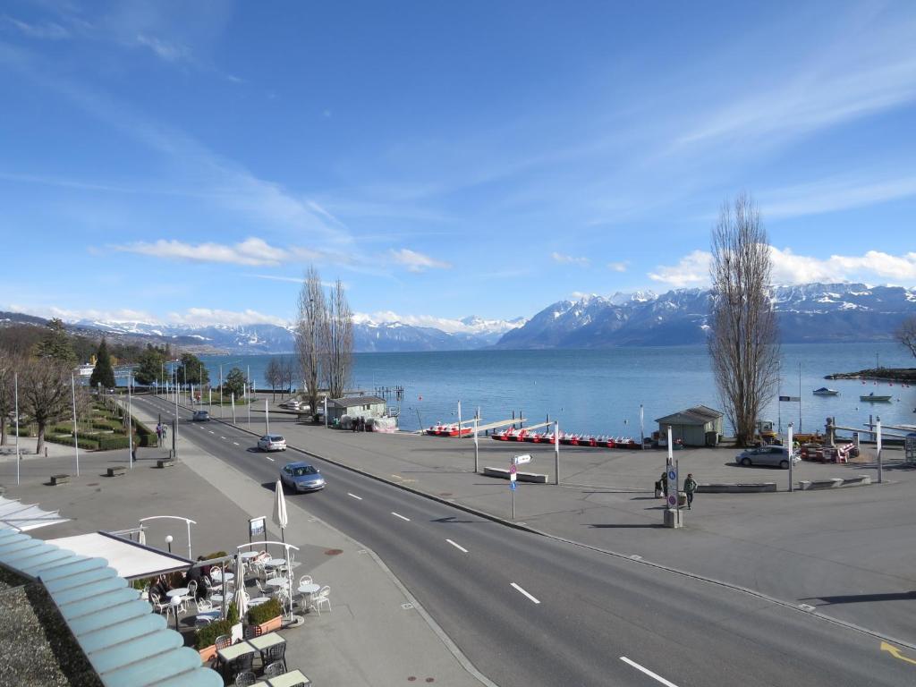 a road with a view of the water and mountains at Hôtel du Port in Lausanne