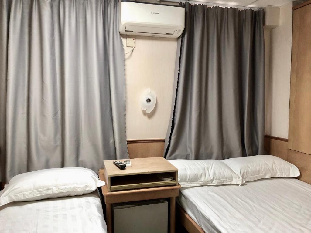 a room with two beds and a window with curtains at Good Fortune Inn in Hong Kong