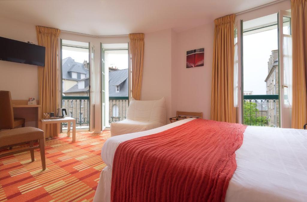 a bedroom with a bed and a desk and windows at Hotel Balmoral Dinard in Dinard