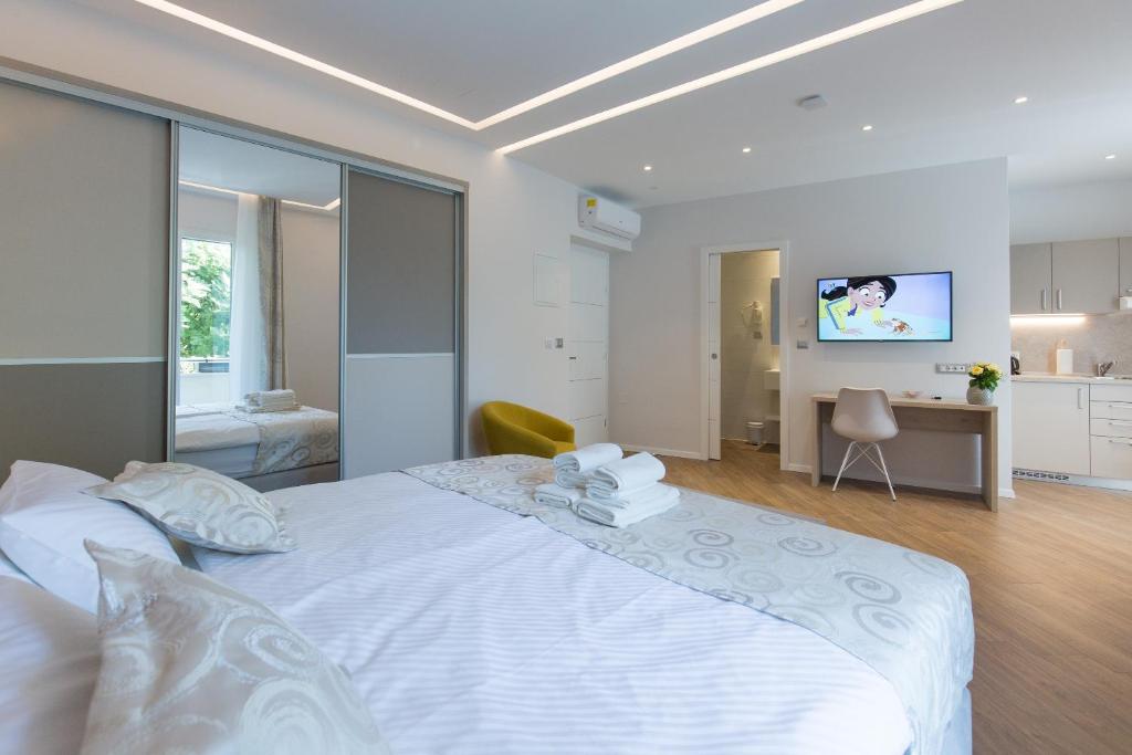 a bedroom with a large white bed and a kitchen at AML apartments in Split