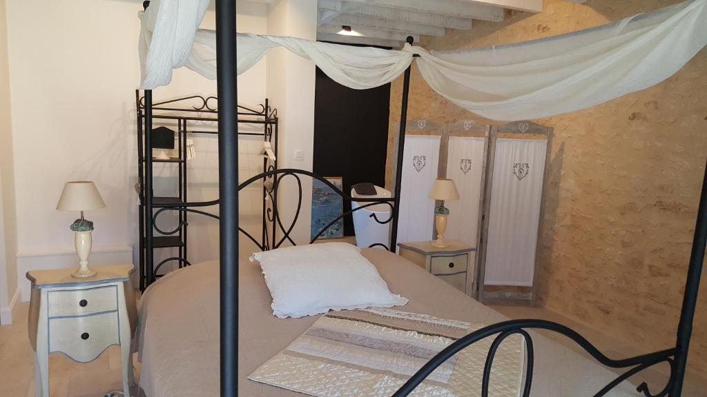 1 dormitorio con 1 cama con dosel, 2 mesas y 2 lámparas en La Manilau, en Le Buisson de Cadouin