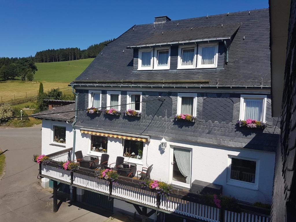 a white house with flower boxes on a balcony at Pension Bergfrieden in Schmallenberg