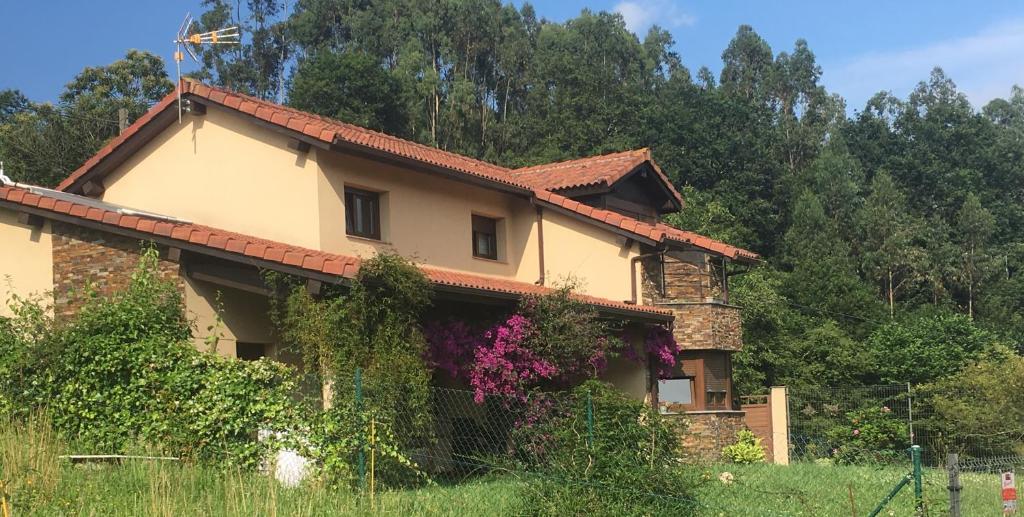 una casa con flores a un lado. en Acogedora Casa en Asturias, en Candamin