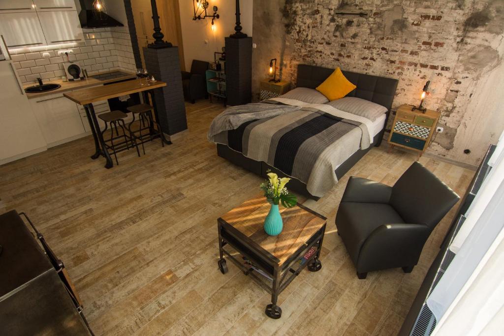 ein Schlafzimmer mit einem Bett, einem Stuhl und einem Tisch in der Unterkunft Mini Loft Apartman in Eger