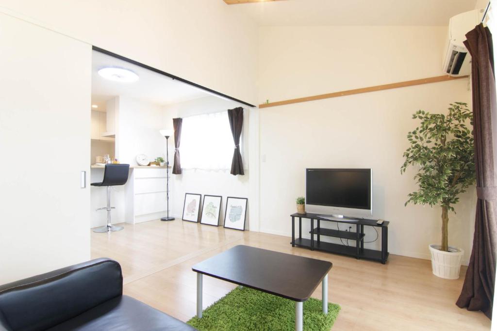 a living room with a tv and a table at Guesthouse Tokushima in Tokushima