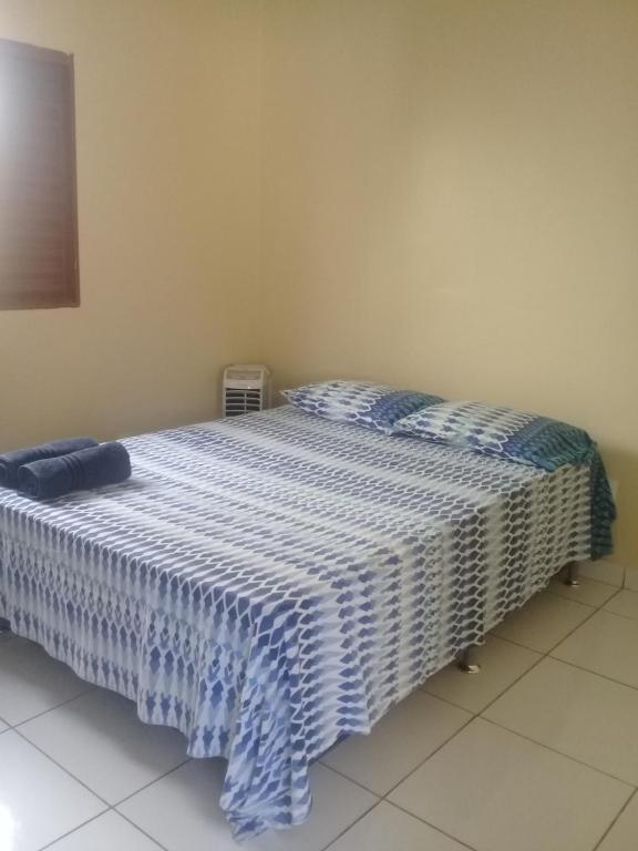 a bedroom with a bed with a blue and white blanket at Pousada Acolhedora Unidade II in Ribeirão Preto