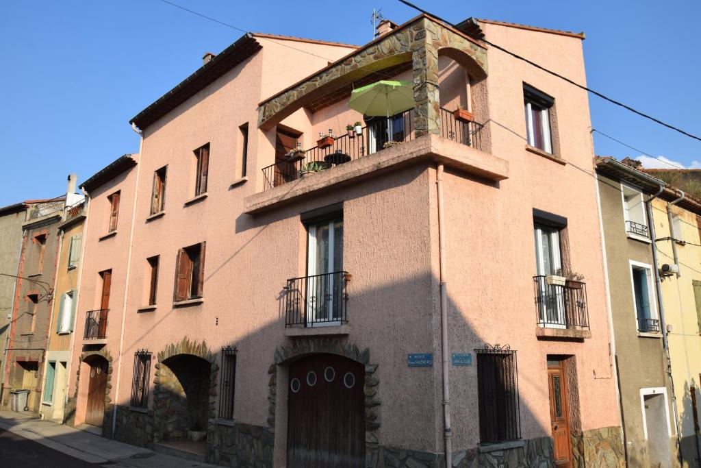 un grande edificio in mattoni con balcone con ombrellone di Estagel a Estagel