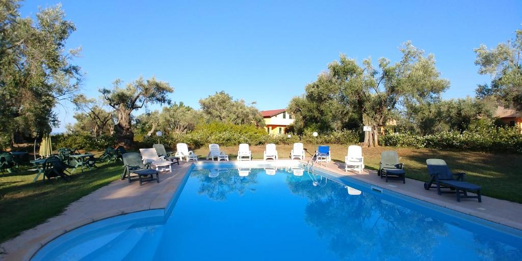 uma piscina com espreguiçadeiras e cadeiras de jardim ao lado em La Piana degli Ulivi em Rossano