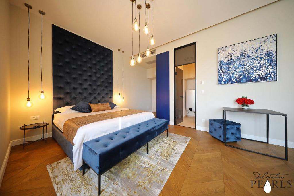 a bedroom with a large bed with a blue headboard at Three Pearls Deluxe Rooms & Studios in Zadar