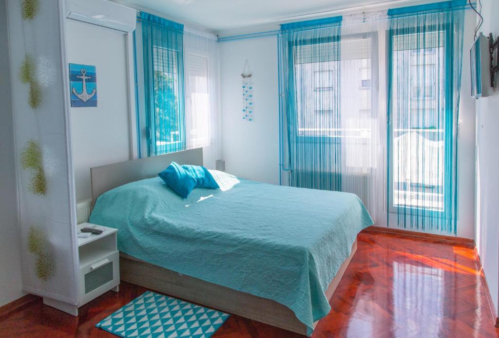 - une chambre avec un lit doté de draps bleus et de fenêtres dans l'établissement Studio apartman Tirkiz, à Zagreb