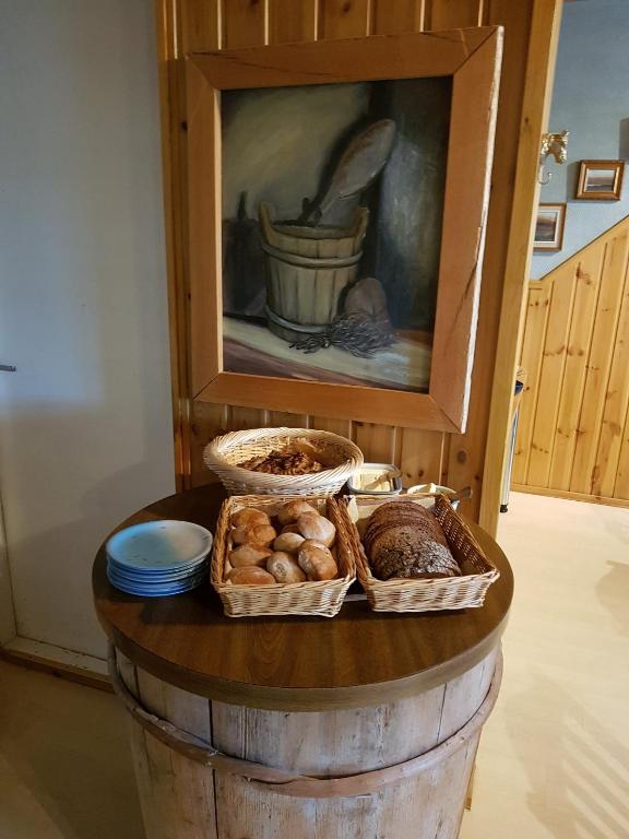 a table with three baskets of bread and a painting at Paimentupa in Kolinkylä