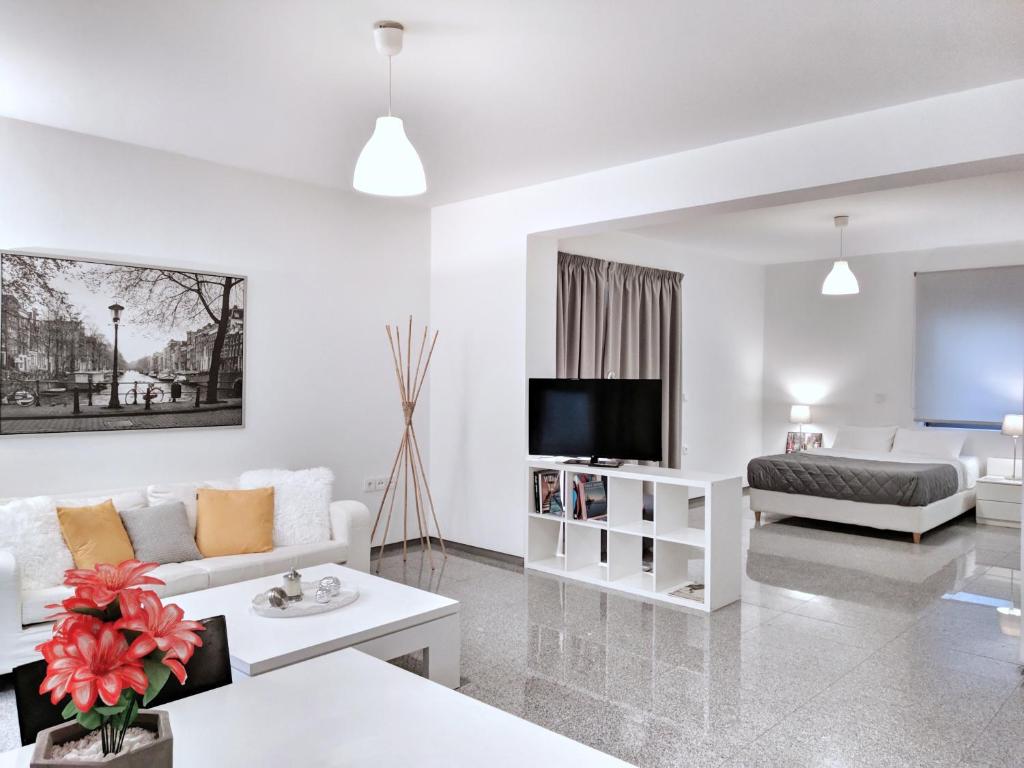 a white living room with a couch and a tv at Brand new budget apartment next to Iaso and Oaka in Athens