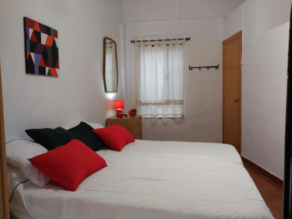 - une chambre avec un grand lit blanc et des oreillers rouges dans l'établissement Ca la Motrila, à Buñol