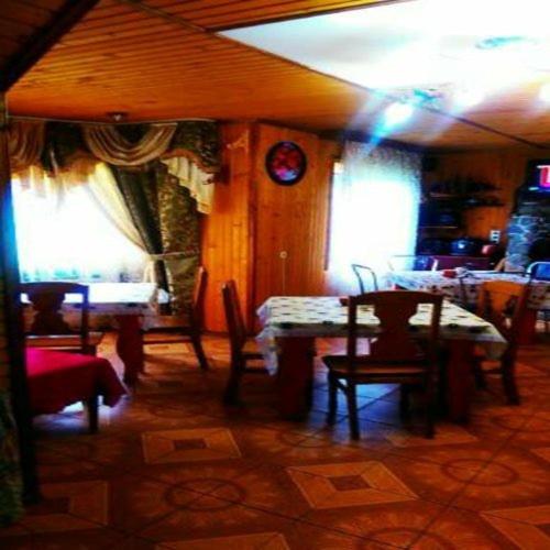 a dining room with a table and chairs and windows at Kovcheg Holiday Home in Mykulychyn