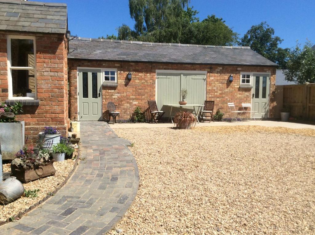 a brick house with a patio and a yard at The Rear of the Plough,Everdon. in Daventry