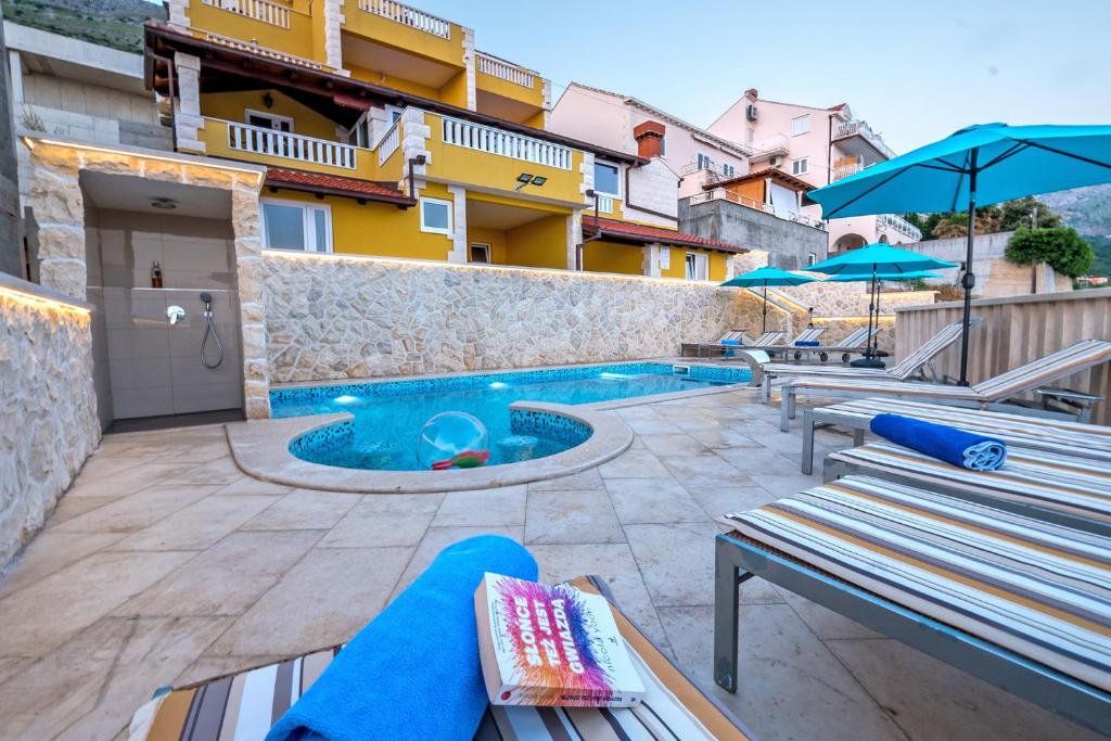 a patio with a pool and benches and a building at Villa Sunset in Mlini