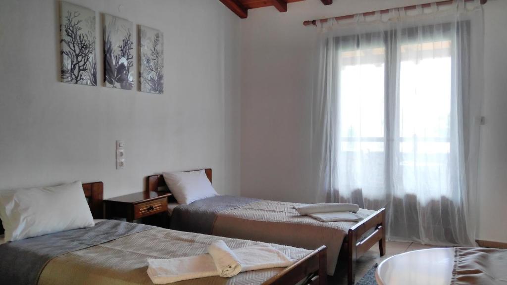 a hotel room with two beds and a window at Villa Maraki in Agia Paraskevi