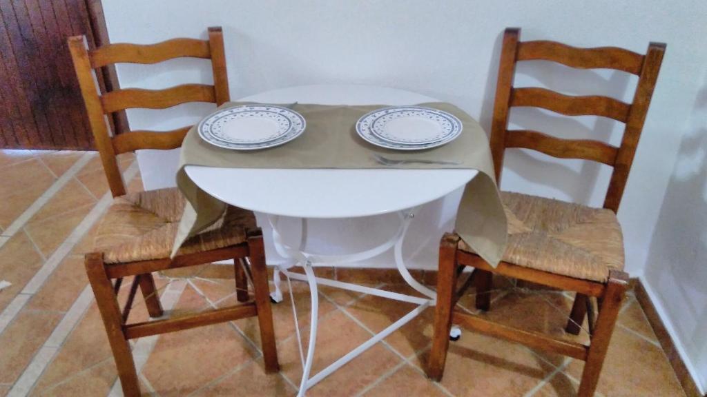 a white table with two plates and two chairs at Villa Maraki in Agia Paraskevi