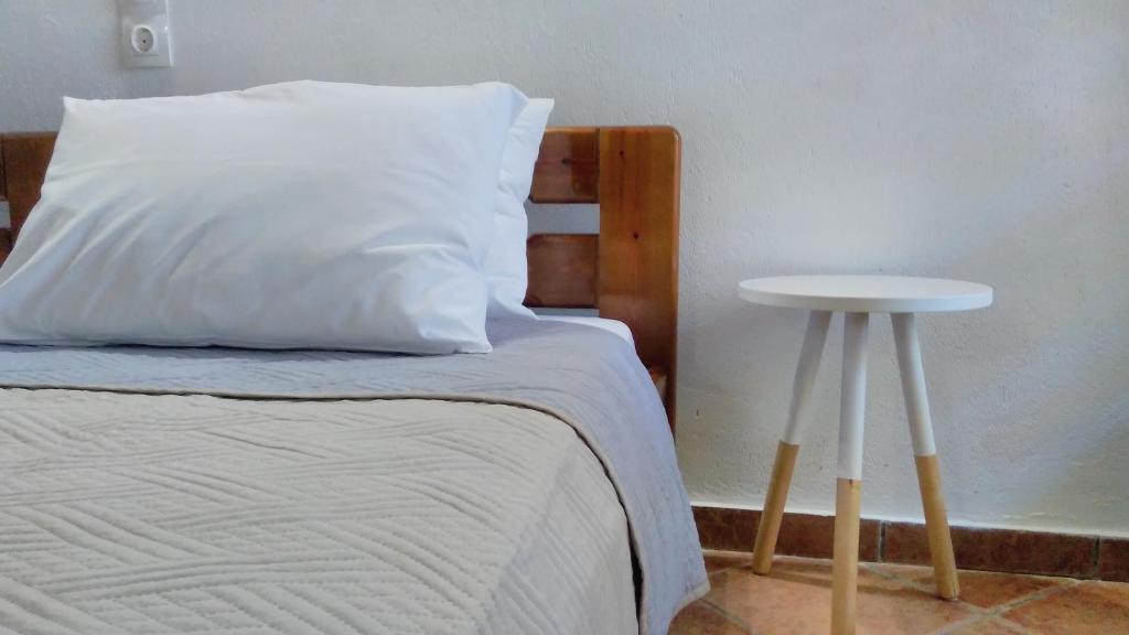 a bed with a white pillow and a side table at Villa Maraki in Agia Paraskevi