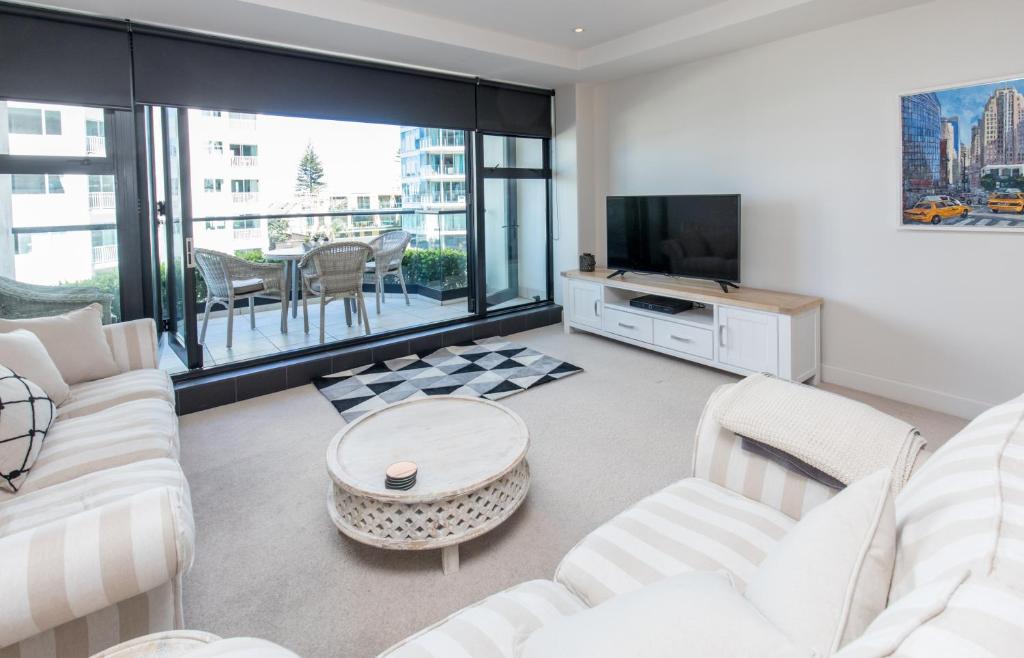 a living room with white furniture and a large window at Ocean Eleven 25 in Mount Maunganui
