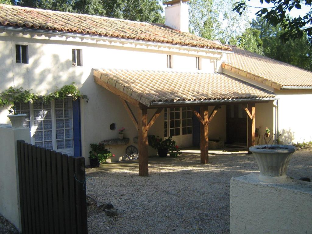 a house with a wooden pergola in the yard at Chez Clemley in Lezay