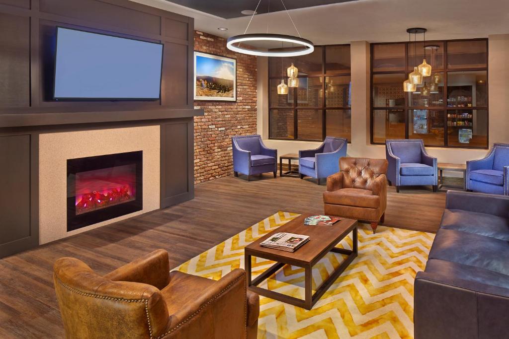 a living room with a fireplace and a flat screen tv at Scholar Morgantown, Tapestry Collection by Hilton in Morgantown