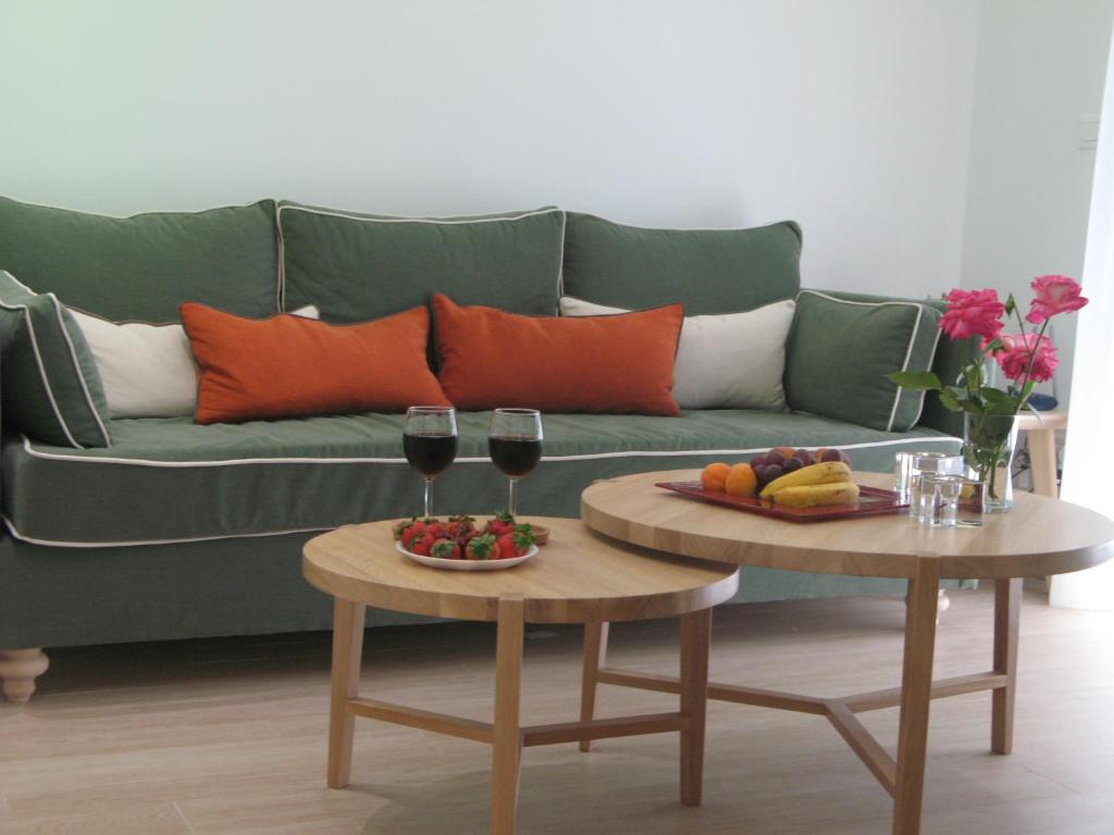 um sofá verde com duas mesas com copos de vinho em Elegant Acropolis em Atenas