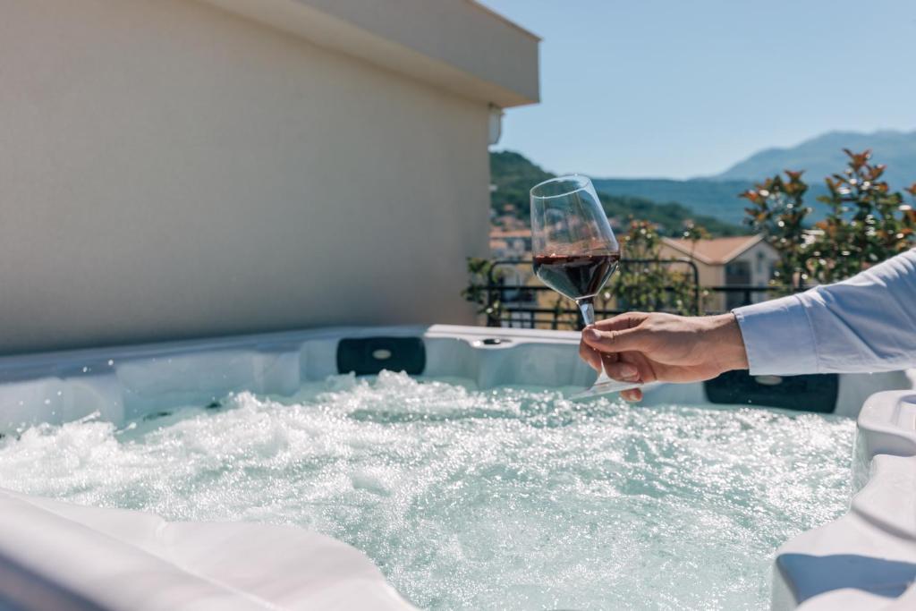a person holding a glass of wine in a hot tub at Villa Royal Apartments in Tivat