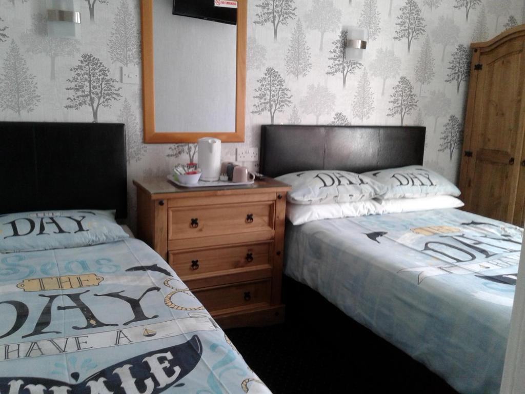 two beds sitting next to each other in a bedroom at Roachvale - Couples & Families - Room only in Blackpool