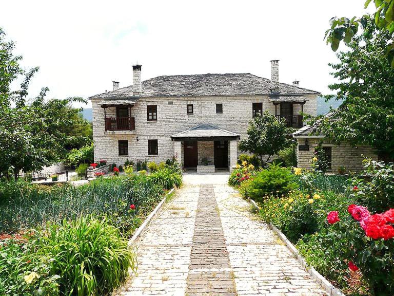 a stone walkway leading to a large stone house at Aloni Guesthouse in Ano Pedina