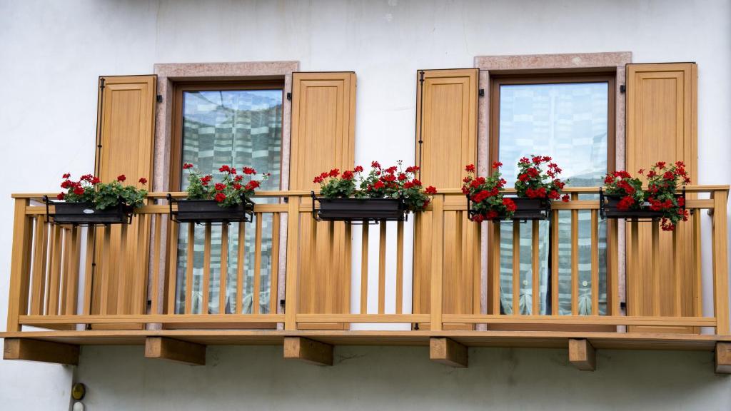 コマーノ・テルメにあるNido di Rondine B&Bの木製バルコニー(花の咲く窓3つ付)
