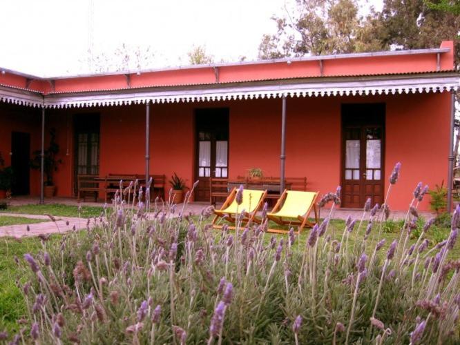 a red building with tables and chairs in front of it at Hostería Rural Les Aldudes in San Andrés de Giles